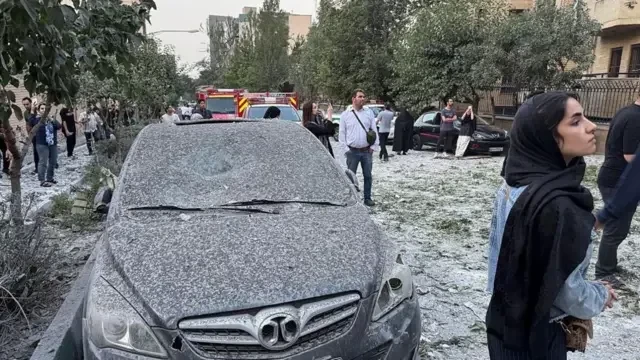 Carro repleto de cinzas, aparentemente, com pessoas em volta