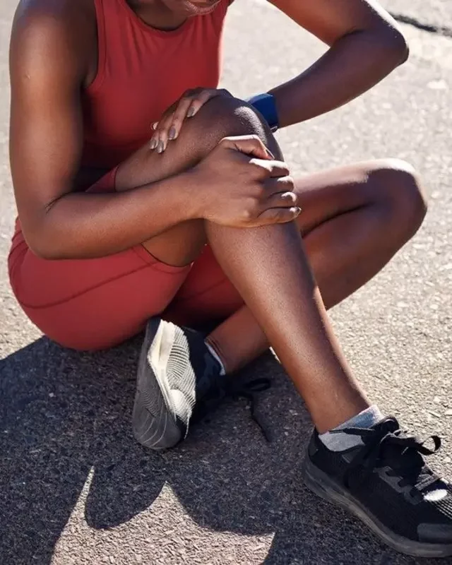 Mulher com as mãos no joelho durante exercício